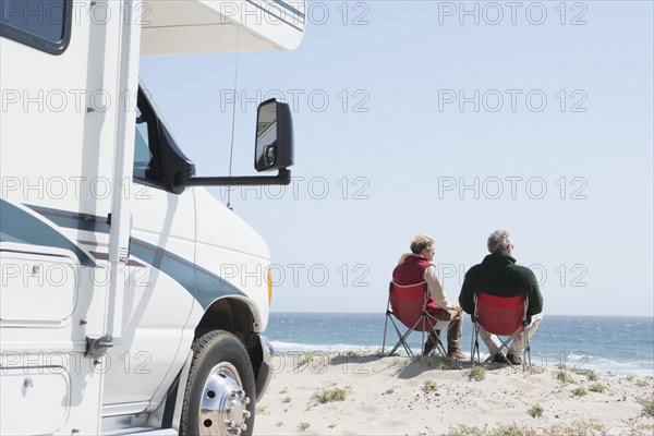 Senior Caucasian couple in lawn chairs overlooking ocean