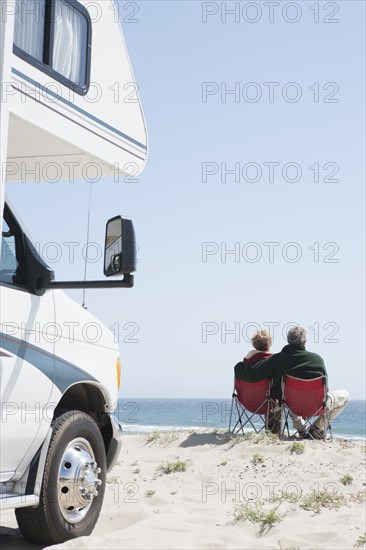 Senior Caucasian couple in lawn chairs overlooking ocean