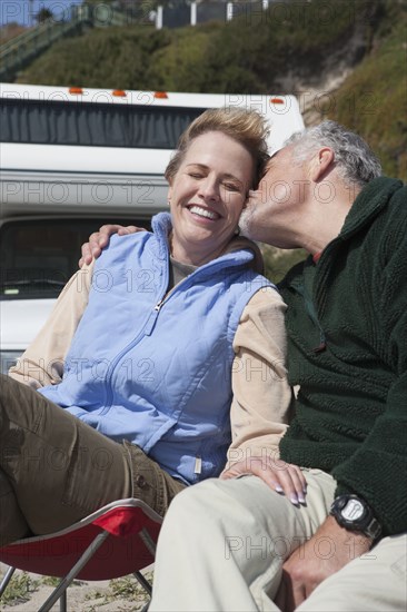 Caucasian couple kissing in lawn chairs