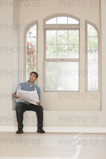 Hispanic man reading blueprints in new home