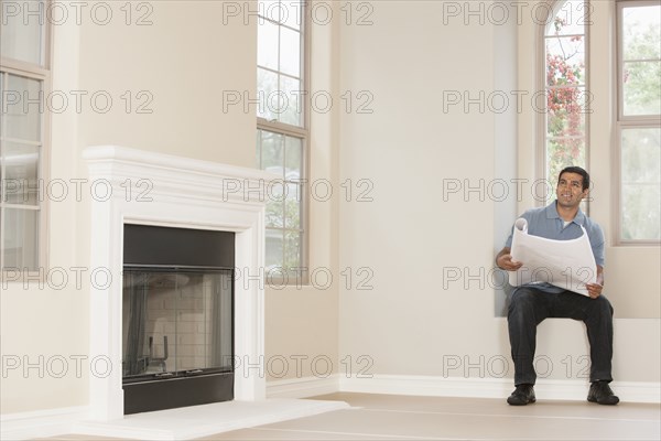 Hispanic man reading blueprints in new home