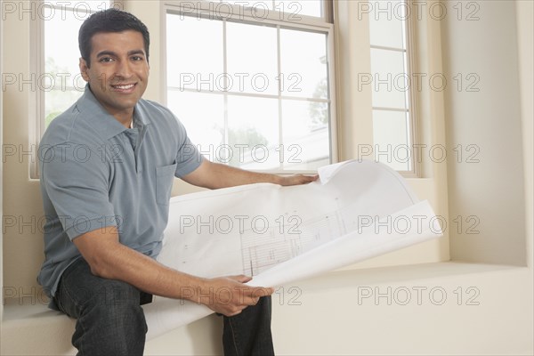 Hispanic man reading blueprints in new home