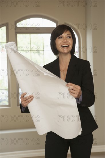 Mixed race realtor holding blueprints in empty home