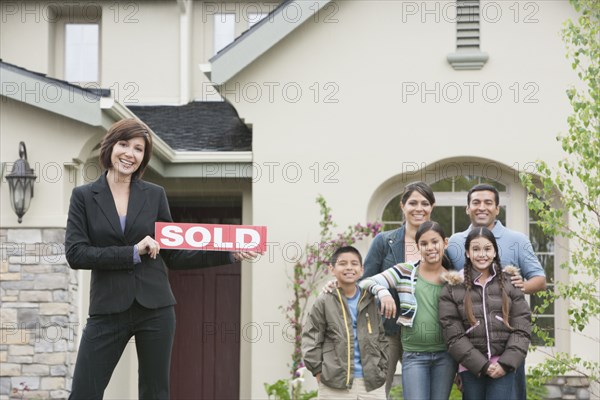 Realtor and family smiling outside new home