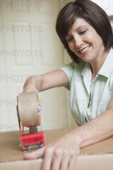 Mixed race woman packing cardboard box