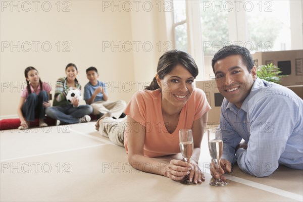 Hispanic couple drinking champagne in new home