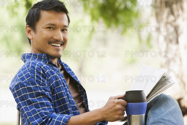 Asian man relaxing in lawn chair outdoors