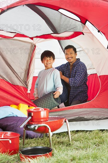 Asian father and son unpacking in tent