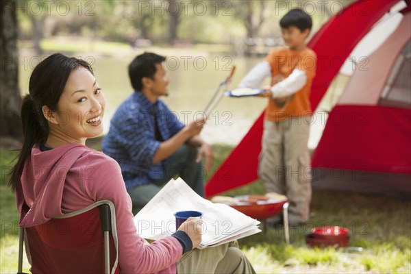 Asian family relaxing at campsite