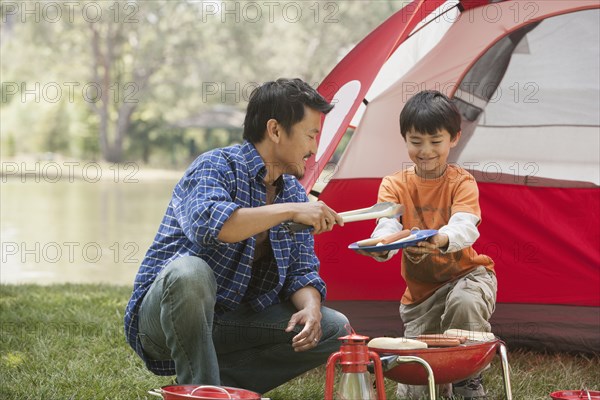 Father and son cooking at campsite