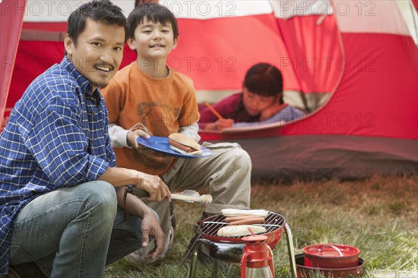 Father and son cooking at campsite