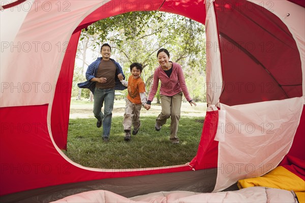Asian family running to tent at campsite