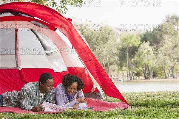 Couple reading newspaper together in tent