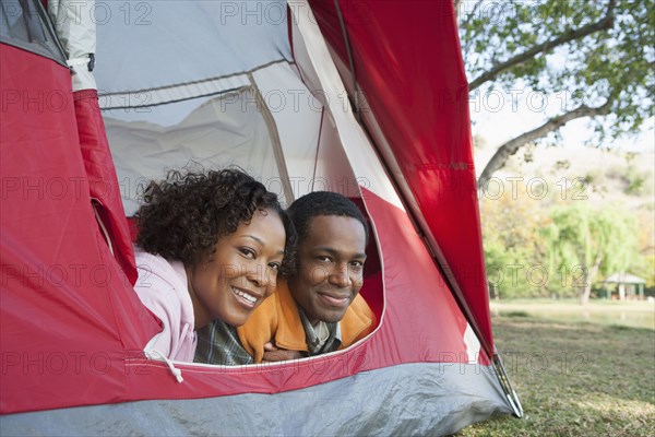 Couple peeking out of tent at campsite