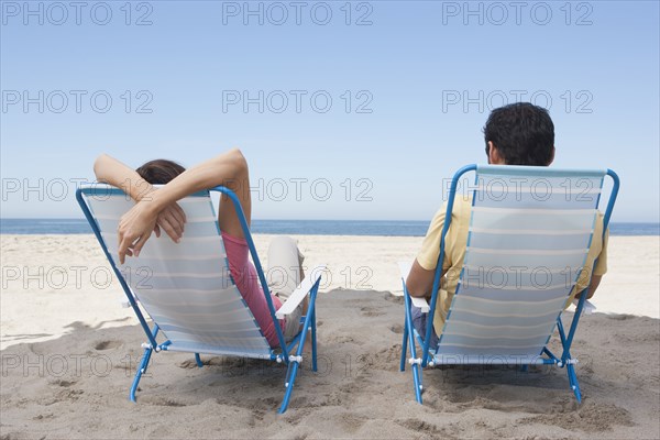 Couple relaxing in lawn chairs on beach