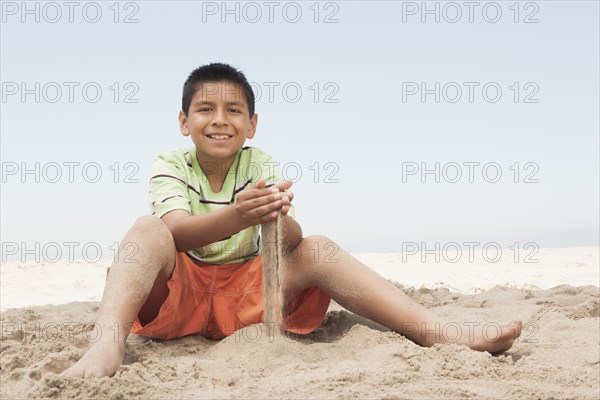 Hispanic boy playing in sand on beach