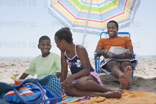 Father and children relaxing together on beach