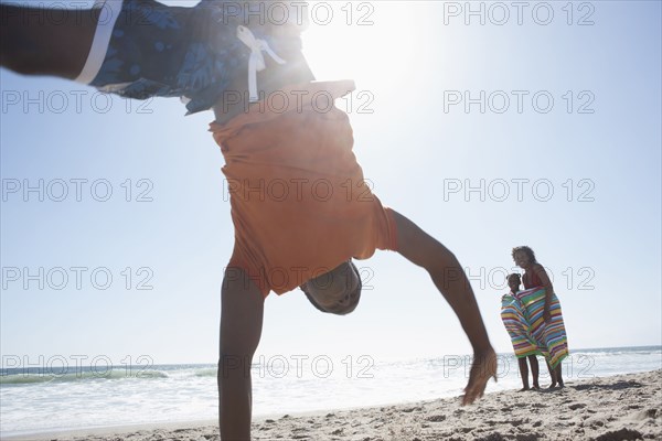 Boy doing cartwheel on beach