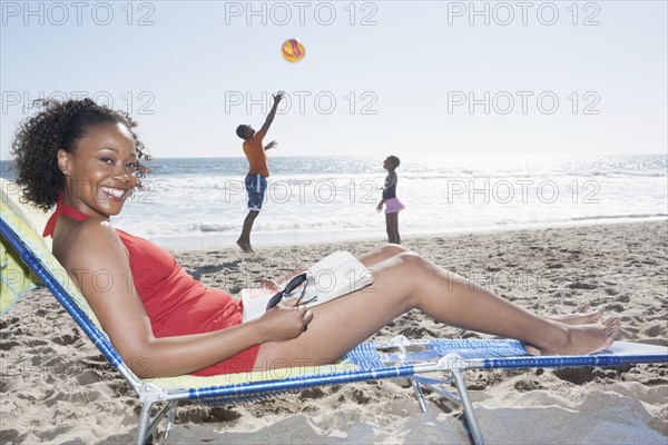 Mother relaxing while children as on beach