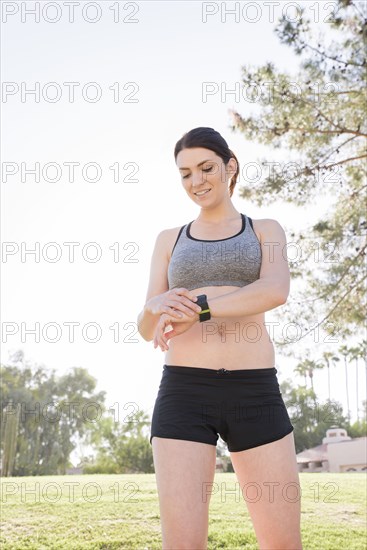 Caucasian woman standing in grass checking the time on wristwatch