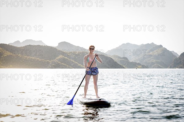 Caucasian woman standing on paddleboard in river