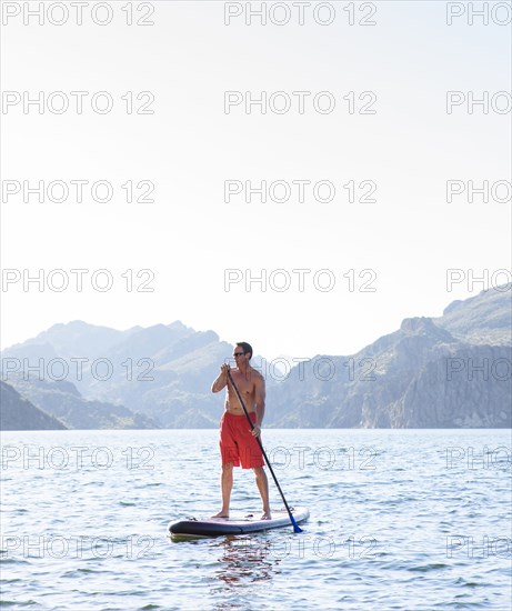Hispanic man on paddleboard in river