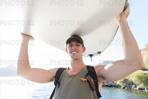 Caucasian man carrying paddleboard at river