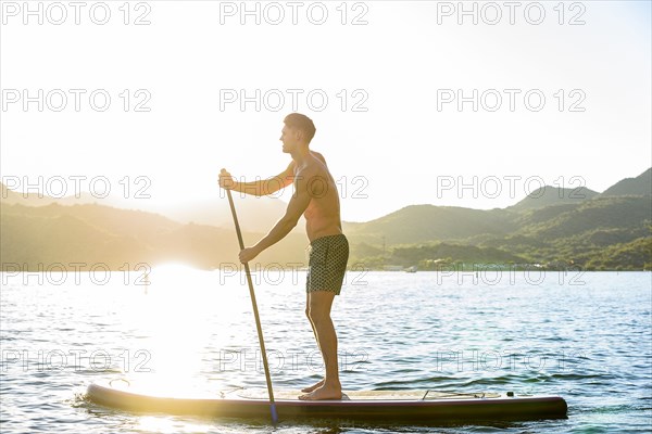 Caucasian man standing on paddleboard in river