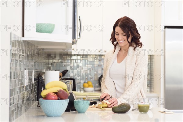 Caucasian woman cutting fruit in domestic kitchen