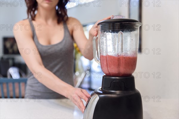Caucasian woman mixing fruit smoothie in blender
