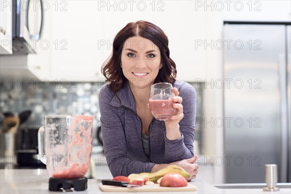 Caucasian woman drinking fruit smoothie in domestic kitchen