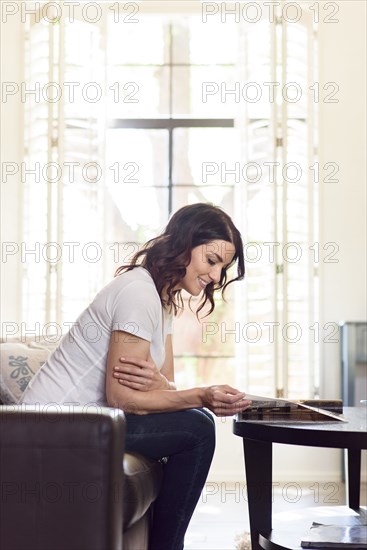 Caucasian woman sitting on sofa reading magazine