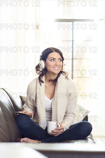 Caucasian woman sitting on sofa listening to headphones