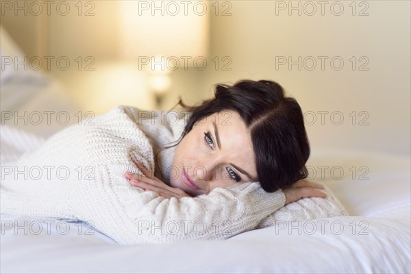 Caucasian woman daydreaming on bed