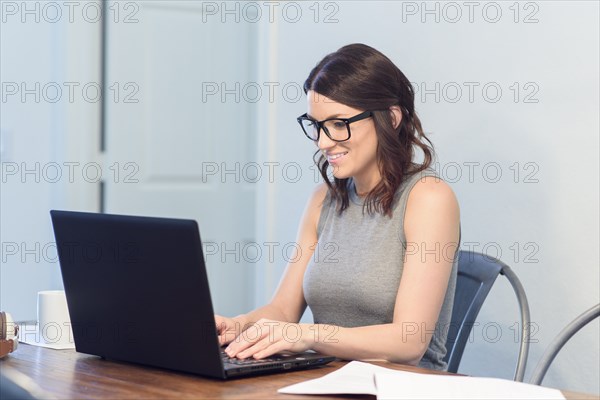 Caucasian woman wearing eyeglasses using laptop