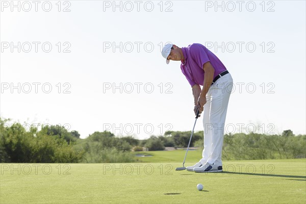 Hispanic golfer putting on golf course