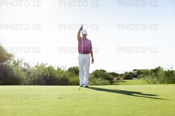 Hispanic golfer aiming on golf course