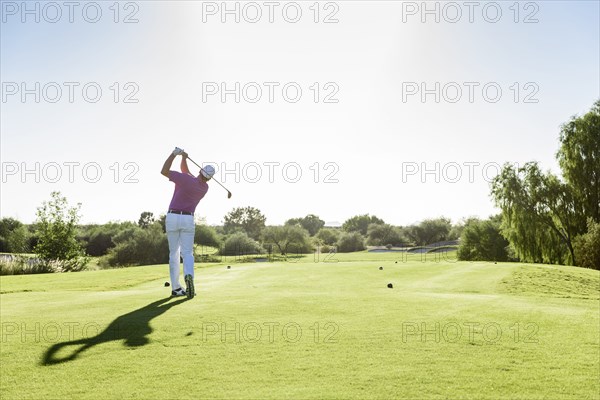 Hispanic golfer teeing off on golf course