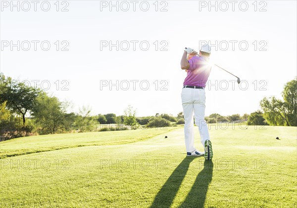 Hispanic golfer teeing off on golf course