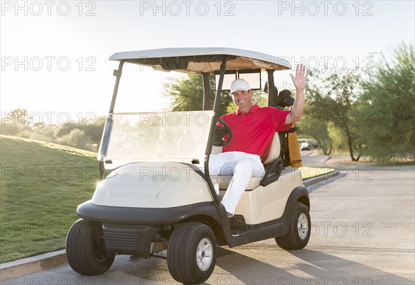 Portrait of Hispanic golfer waving in golf cart