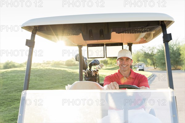 Portrait of Hispanic golfer driving golf cart