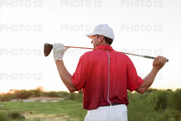 Hispanic golfer holding golf club on shoulders