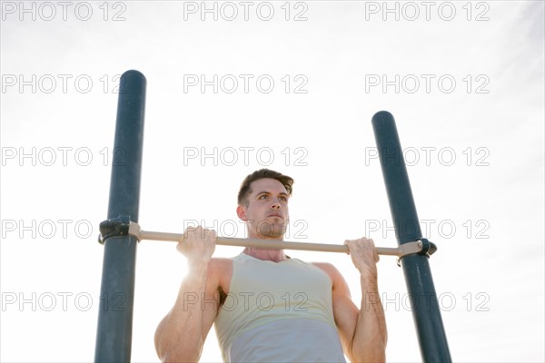 Caucasian man doing chin-up outdoors