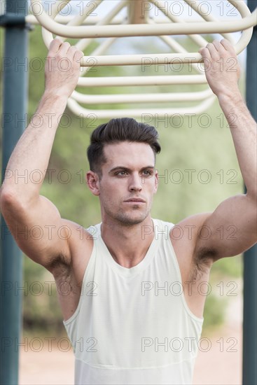 Caucasian man holding onto monkey bars outdoors
