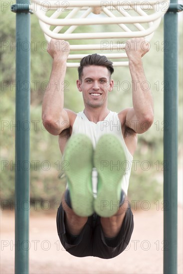 Caucasian man hanging on monkey bars outdoors