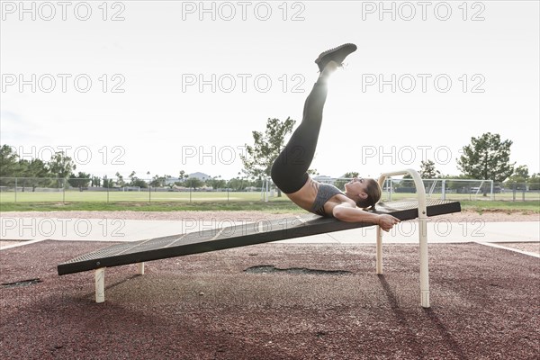 Hispanic woman doing leg lifts outdoors