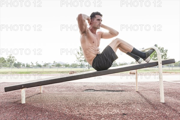 Caucasian man doing sit-ups outdoors