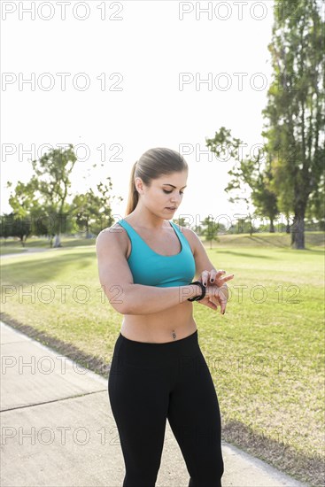 Hispanic woman checking the time on wristwatch in park