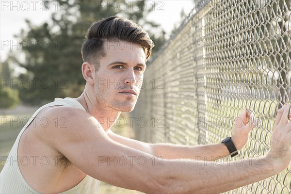 Caucasian man leaning on fence and resting