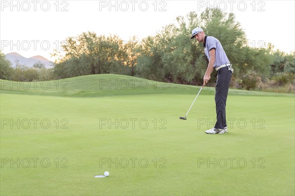 Caucasian golfer putting on golf course